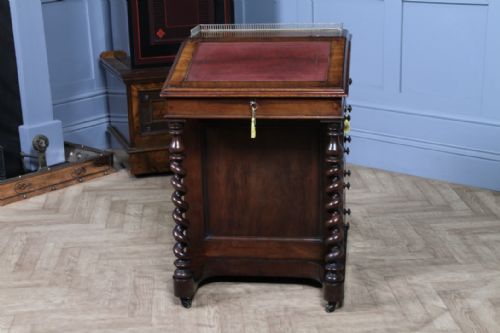 fig 3. An early Victorian mahogany Davenport desk featuring a sloped writing surface with red leather inset, brass top gallery, barley twist front supports, and four side drawers.