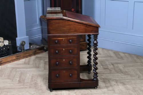 fig 4. An early Victorian mahogany Davenport desk featuring a sloped writing surface with red leather inset, brass top gallery, barley twist front supports, and four side drawers.
