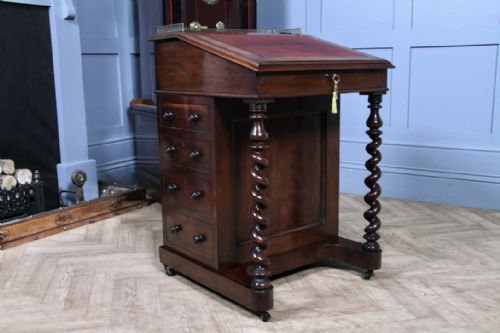 fig 5. An early Victorian mahogany Davenport desk featuring a sloped writing surface with red leather inset, brass top gallery, barley twist front supports, and four side drawers.