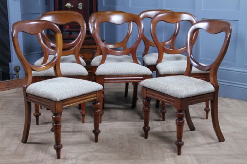 fig 1. A set of eight antique Victorian mahogany dining chairs featuring rounded balloon backrests, turned front legs, and textured neutral upholstered seats.