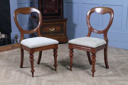 fig 2. A set of eight antique Victorian mahogany dining chairs featuring rounded balloon backrests, turned front legs, and textured neutral upholstered seats.