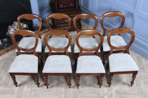 fig 4. A set of eight antique Victorian mahogany dining chairs featuring rounded balloon backrests, turned front legs, and textured neutral upholstered seats.