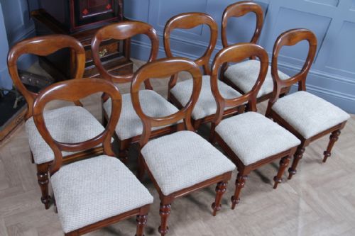 fig 5. A set of eight antique Victorian mahogany dining chairs featuring rounded balloon backrests, turned front legs, and textured neutral upholstered seats.