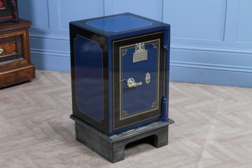 fig 1. A restored Victorian navy blue and black cast iron safe featuring polished brass hardware and a makers plaque, raised on a dark wooden plinth.