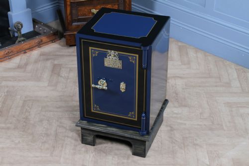 fig 4. A restored Victorian navy blue and black cast iron safe featuring polished brass hardware and a makers plaque, raised on a dark wooden plinth.