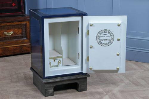 fig 5. A restored Victorian navy blue and black cast iron safe featuring polished brass hardware and a makers plaque, raised on a dark wooden plinth.
