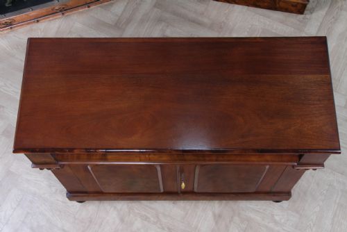 fig 5. A Victorian flame mahogany two-door sideboard featuring a cushion drawer, arched panel doors, carved corbels, and turned bun feet.