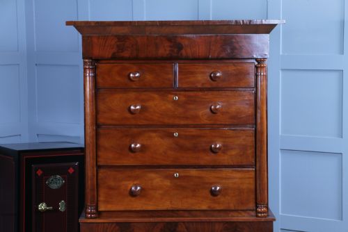 fig 1. A Georgian Scottish mahogany chest on chest featuring eight drawers with turned wooden knobs, fluted side columns, and an overhanging pediment cornice.