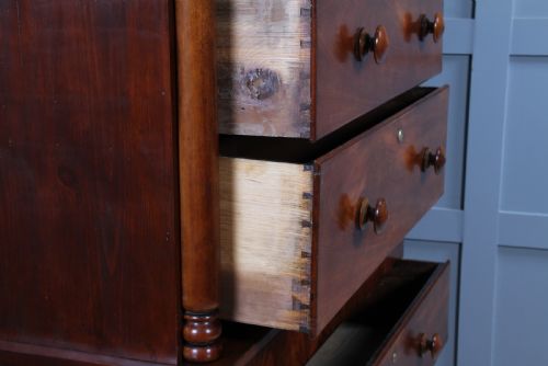 fig 5. A Georgian Scottish mahogany chest on chest featuring eight drawers with turned wooden knobs, fluted side columns, and an overhanging pediment cornice.