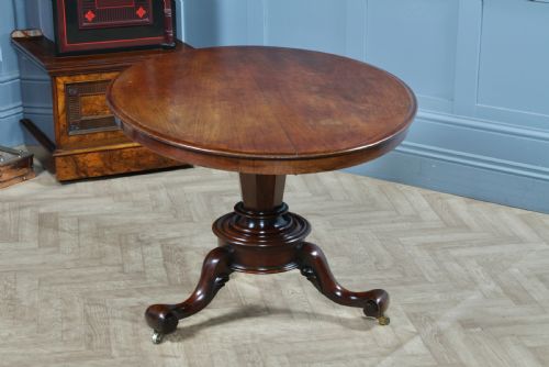fig 2. A Victorian oval mahogany tilt-top dining table supported by an octagonal column and a carved tripod base with brass castors.