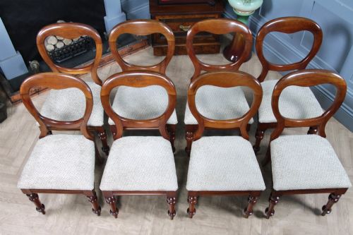 fig 4. A set of eight Victorian mahogany dining chairs featuring open rounded balloon backs, turned front legs, and neutral patterned upholstered seats.