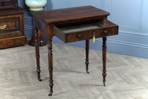 fig 1. A small Georgian flame mahogany side table featuring a single drawer with turned knobs, ring-turned legs, and brass castors.