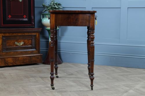 fig 3. A small Georgian flame mahogany side table featuring a single drawer with turned knobs, ring-turned legs, and brass castors.