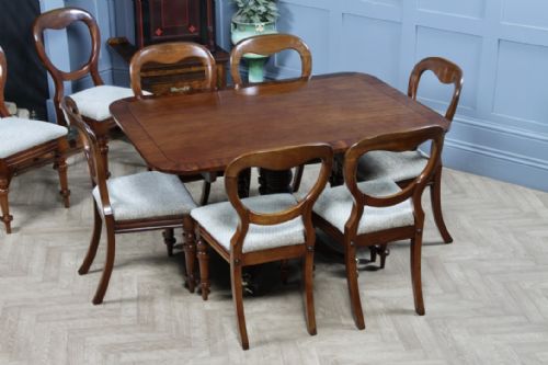 fig 1. A Regency mahogany tilt-top dining table featuring a rectangular crossbanded top supported by a turned pedestal column and four reeded sabre legs with brass castors.