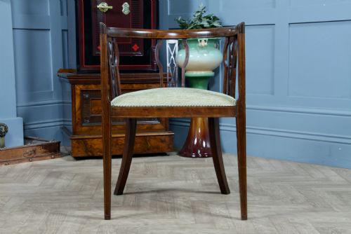 fig 1. An Edwardian inlaid mahogany tub armchair featuring a continuous curved backrest, pierced splats, and a sage green upholstered seat.