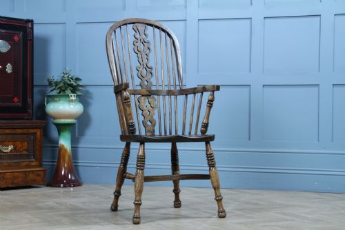 fig 1. A traditional high-back Windsor armchair crafted from ash and elm wood, featuring a pierced central splat, spindled backrest, turned legs, and a cow horn stretcher.
