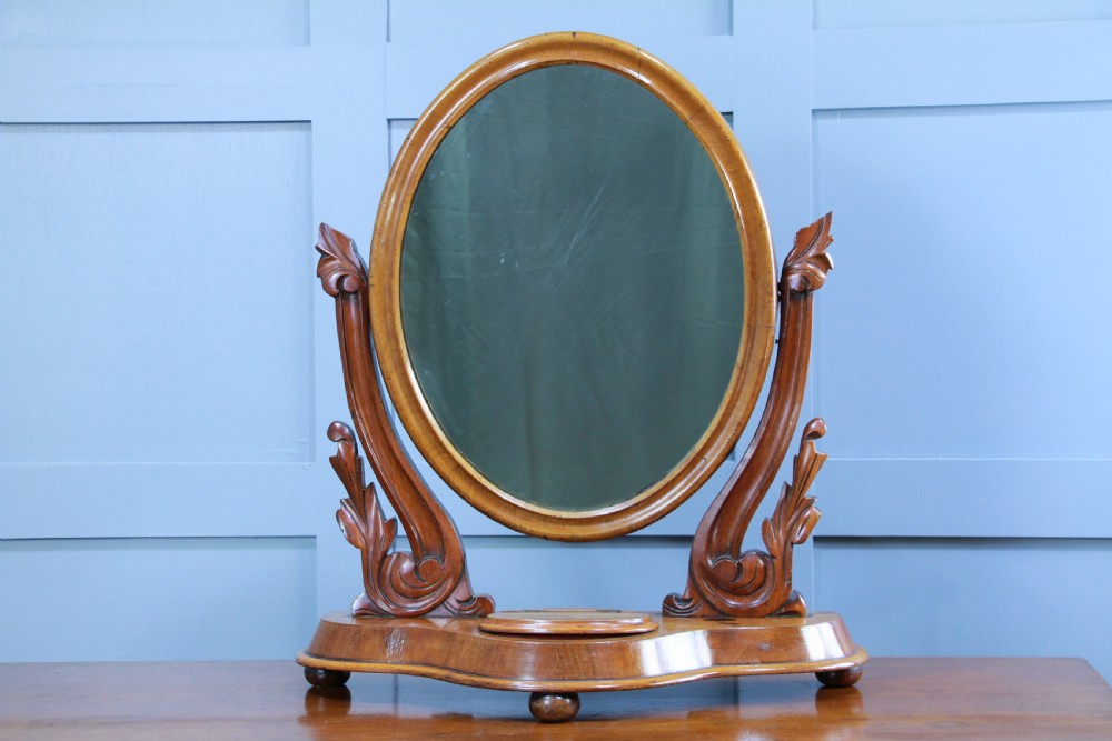 A Victorian mahogany swing toilet mirror featuring an oval moulded frame, carved scroll upright supports, and a shaped plinth base. View II
