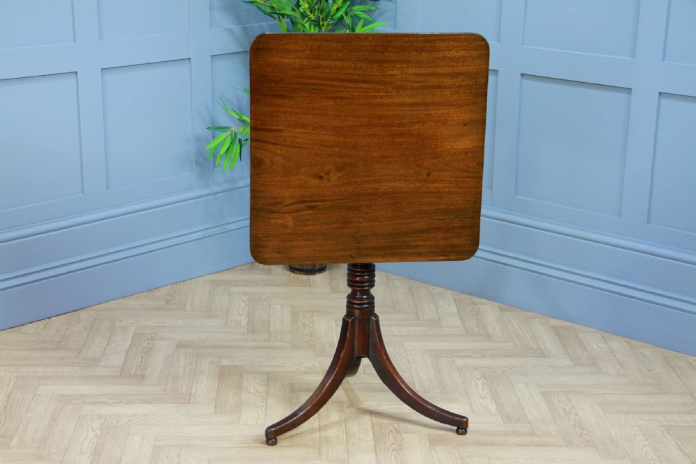 A Regency mahogany tilt-top wine table with a rounded square top, a turned column, and three splayed legs. View II