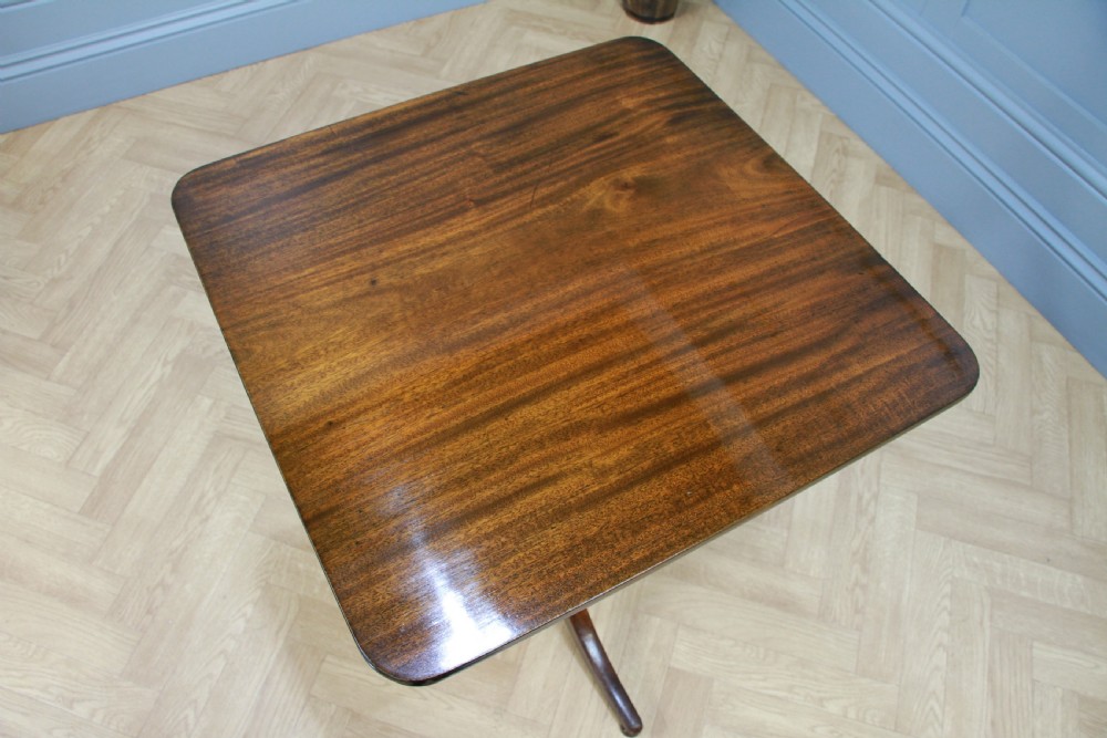 A Regency mahogany tilt-top wine table with a rounded square top, a turned column, and three splayed legs. View IX