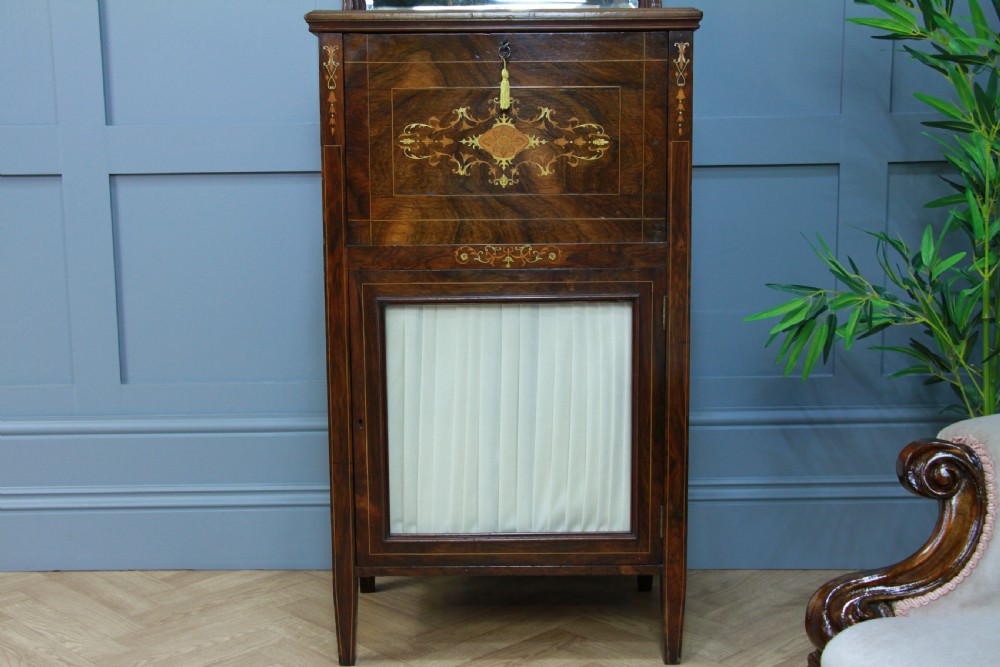 An Edwardian rosewood ladies bureau cabinet featuring marquetry inlay, a mirrored superstructure, a fall-front desk section, and a lower cupboard with a pleated fabric panel. View VII