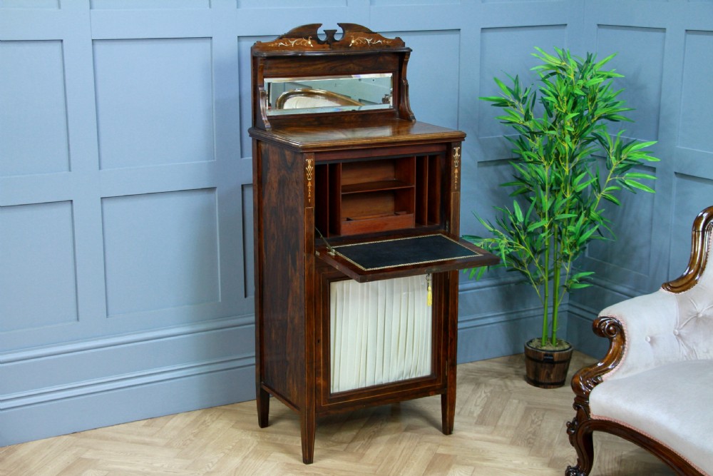 An Edwardian rosewood ladies bureau cabinet featuring marquetry inlay, a mirrored superstructure, a fall-front desk section, and a lower cupboard with a pleated fabric panel. View X