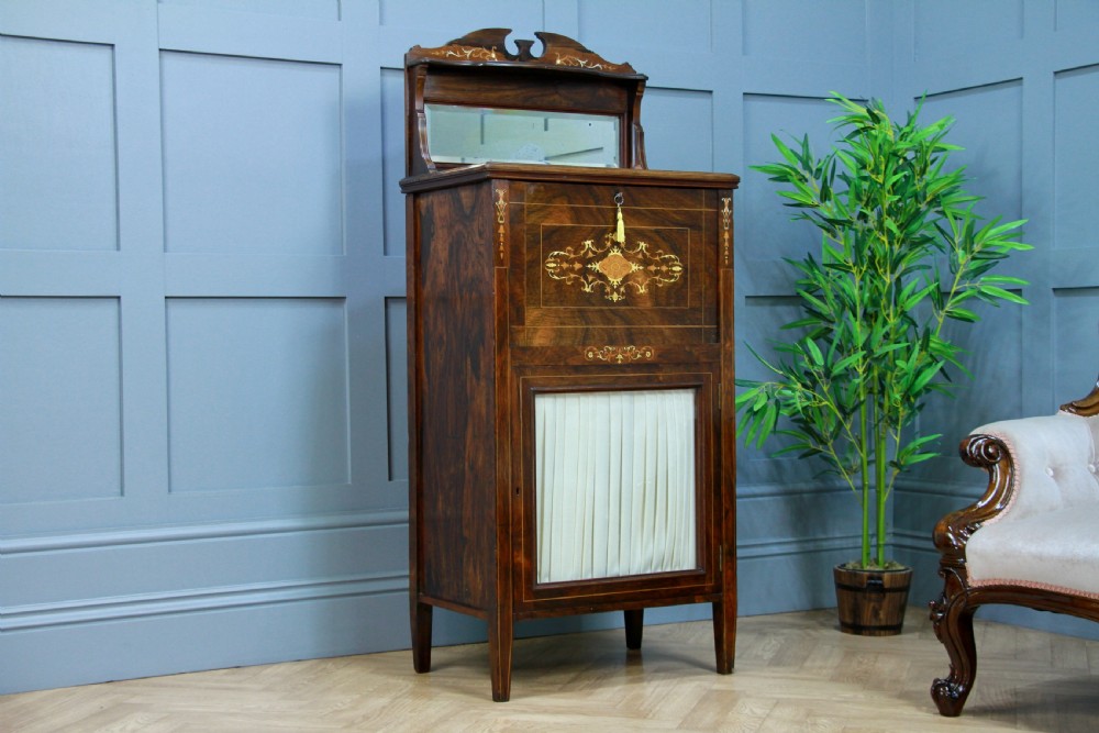 An Edwardian rosewood ladies bureau cabinet featuring marquetry inlay, a mirrored superstructure, a fall-front desk section, and a lower cupboard with a pleated fabric panel. View XI