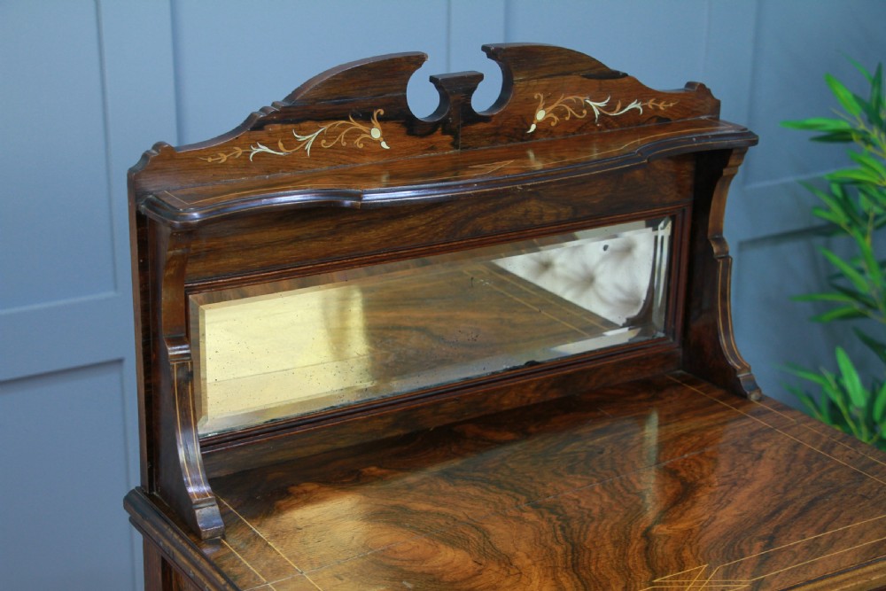 An Edwardian rosewood ladies bureau cabinet featuring marquetry inlay, a mirrored superstructure, a fall-front desk section, and a lower cupboard with a pleated fabric panel. View XVI