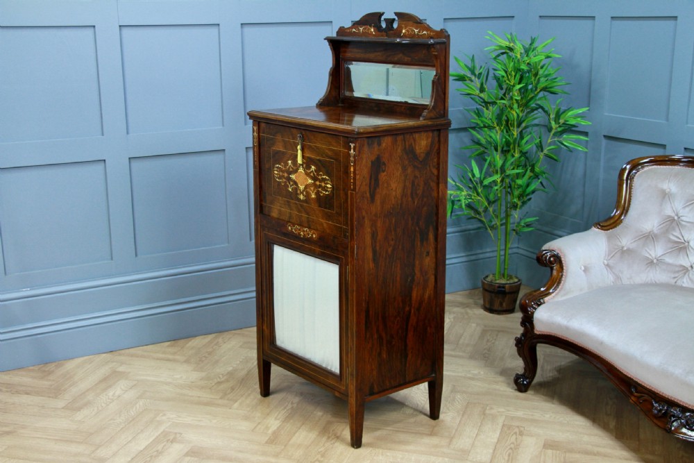 An Edwardian rosewood ladies bureau cabinet featuring marquetry inlay, a mirrored superstructure, a fall-front desk section, and a lower cupboard with a pleated fabric panel. View XVIII
