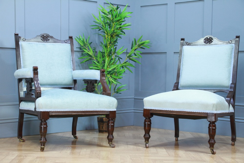 Pair of Edwardian mahogany armchairs upholstered in pale blue fabric featuring carved crestings and turned legs with brass castors. View II