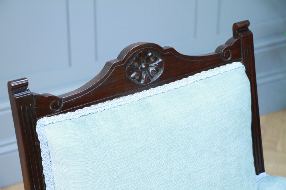 Pair of Edwardian mahogany armchairs upholstered in pale blue fabric featuring carved crestings and turned legs with brass castors. View V