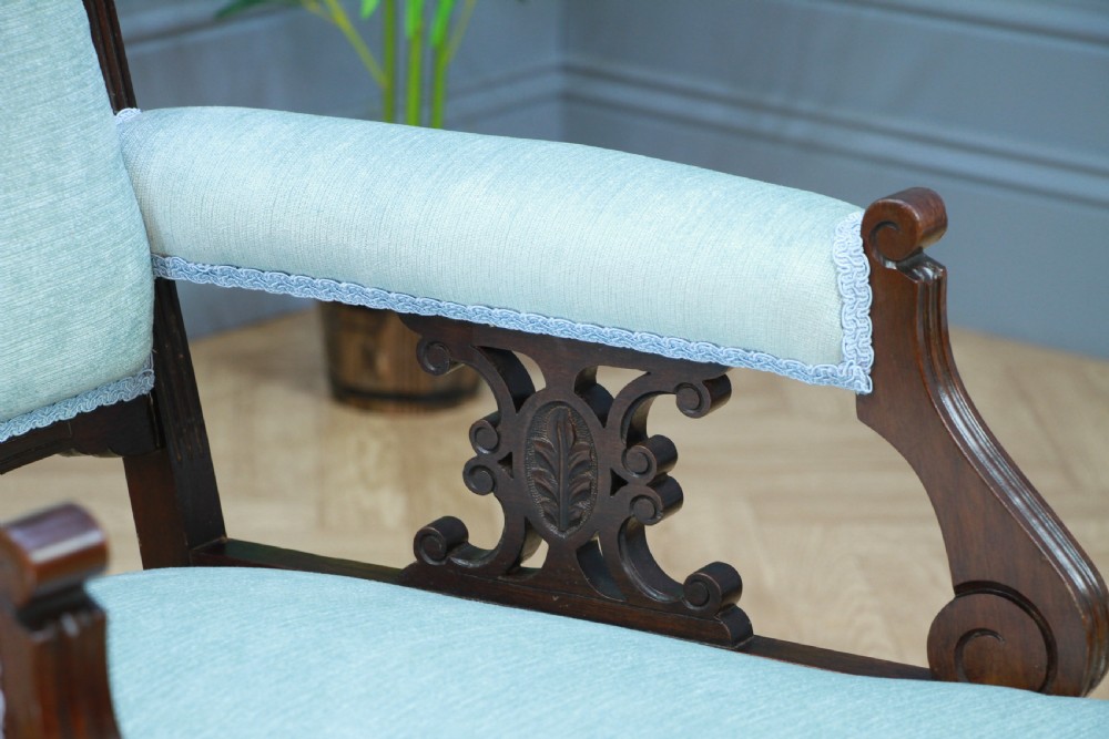 Pair of Edwardian mahogany armchairs upholstered in pale blue fabric featuring carved crestings and turned legs with brass castors. View VIII
