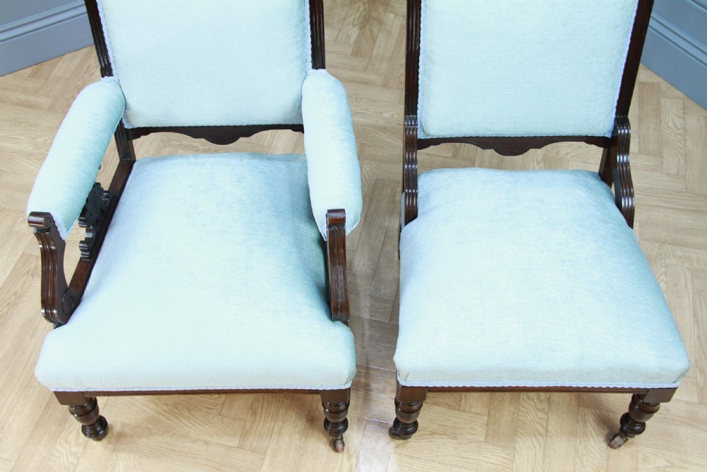 Pair of Edwardian mahogany armchairs upholstered in pale blue fabric featuring carved crestings and turned legs with brass castors. View X