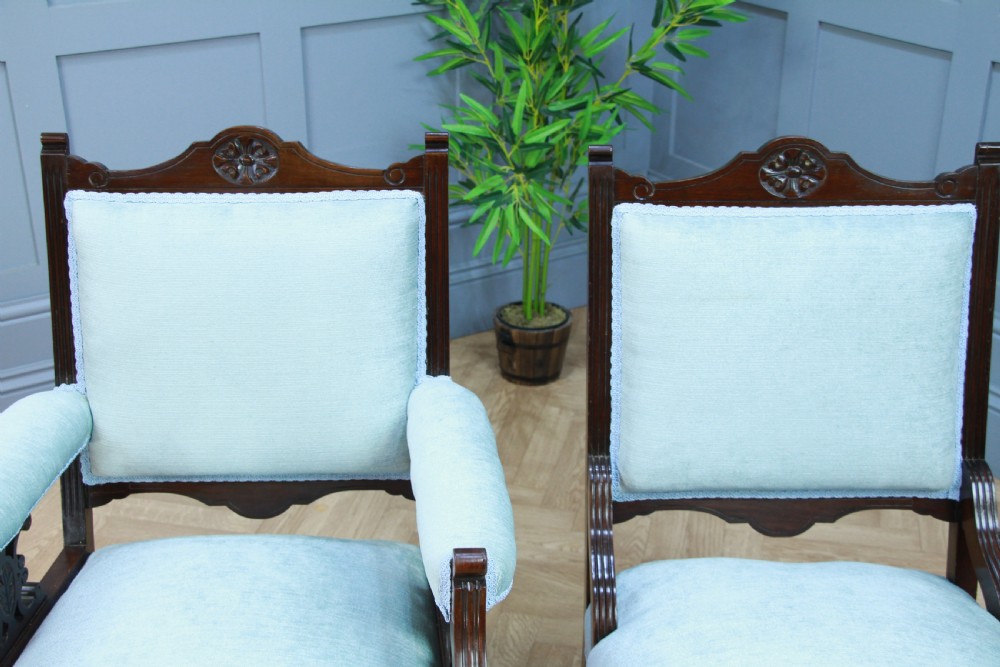 Pair of Edwardian mahogany armchairs upholstered in pale blue fabric featuring carved crestings and turned legs with brass castors. View XII