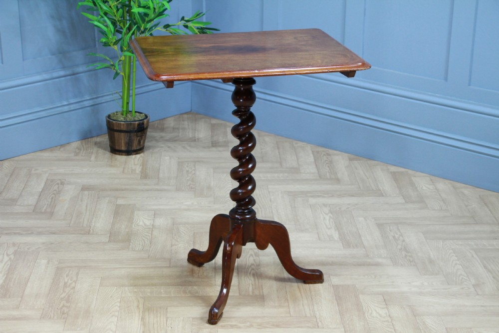 A Victorian flame mahogany tilt-top wine table with a rectangular top, spiral barley twist column, and tripod base.