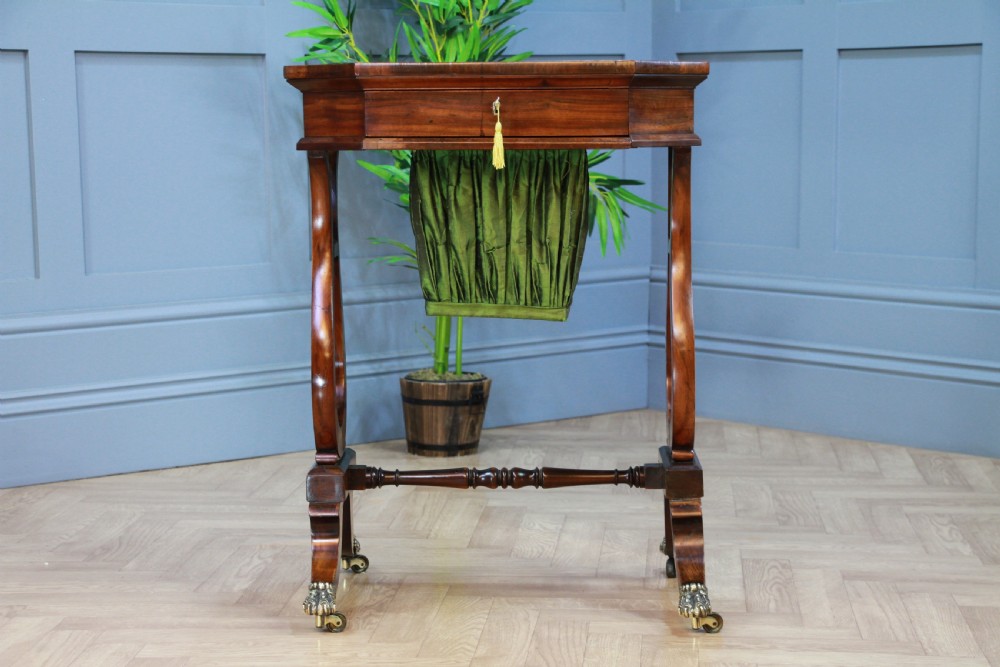 An antique Regency kingwood work table featuring lyre-shaped side supports, a suspended green pleated fabric box, and brass paw feet on castors. View II