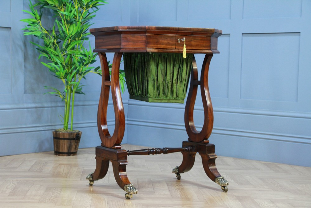 An antique Regency kingwood work table featuring lyre-shaped side supports, a suspended green pleated fabric box, and brass paw feet on castors. View III