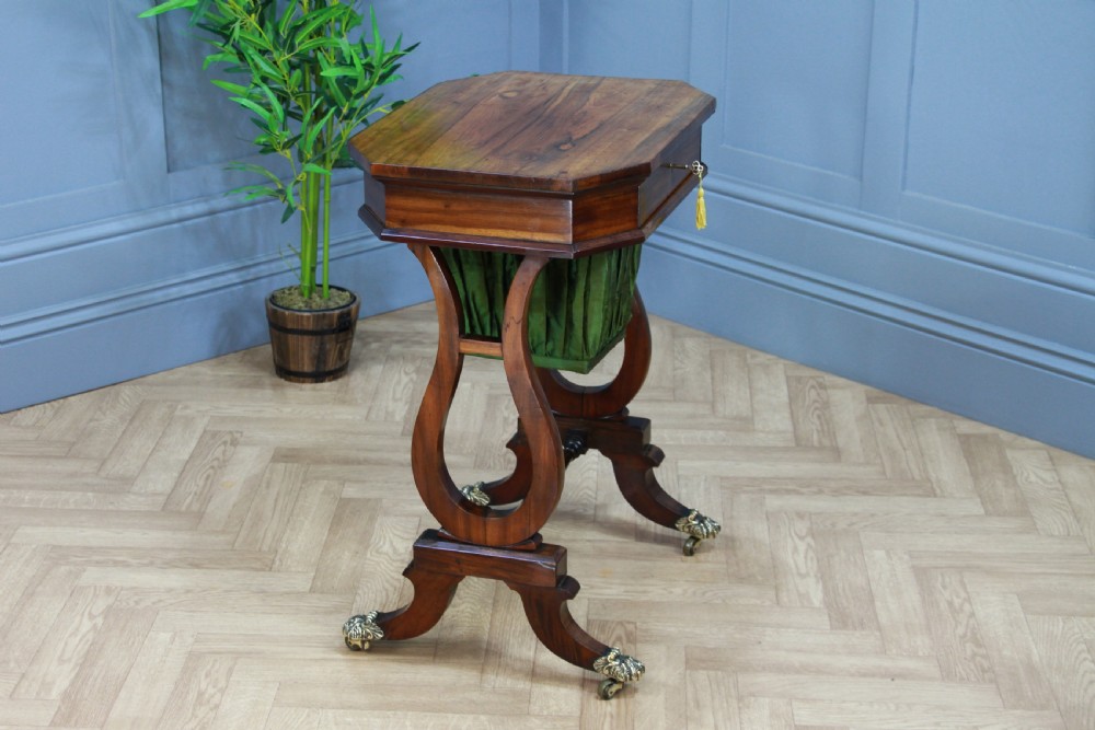 An antique Regency kingwood work table featuring lyre-shaped side supports, a suspended green pleated fabric box, and brass paw feet on castors. View X