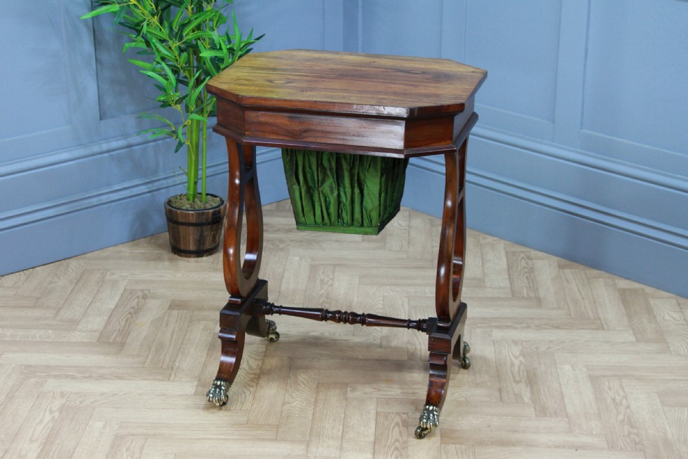 An antique Regency kingwood work table featuring lyre-shaped side supports, a suspended green pleated fabric box, and brass paw feet on castors. View XI