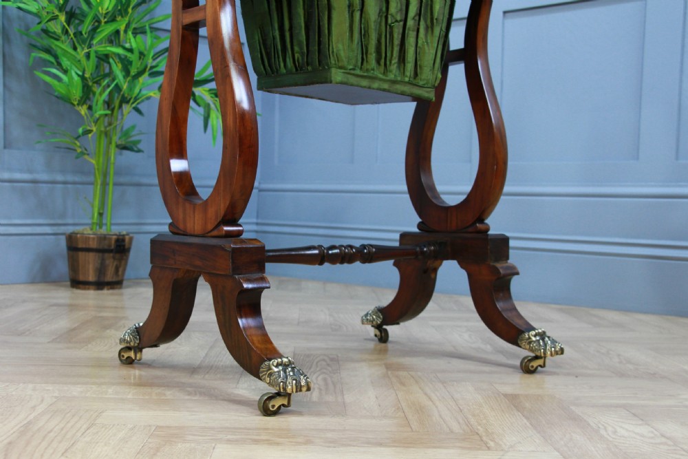 An antique Regency kingwood work table featuring lyre-shaped side supports, a suspended green pleated fabric box, and brass paw feet on castors. View XIII
