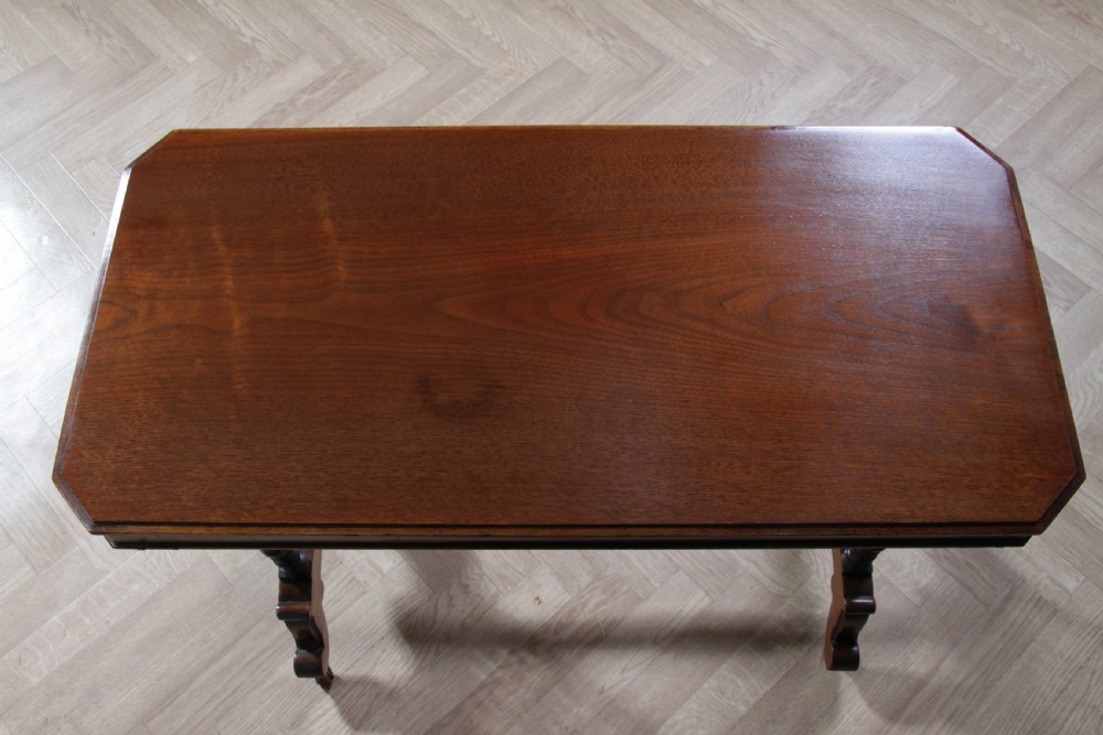 A late Victorian turned walnut occasional table featuring a rectangular top, twin turned end supports, a low stretcher, and feet set on castors. View III