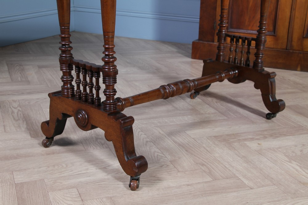 A late Victorian turned walnut occasional table featuring a rectangular top, twin turned end supports, a low stretcher, and feet set on castors. View V