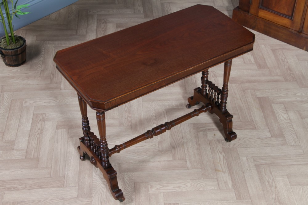 A late Victorian turned walnut occasional table featuring a rectangular top, twin turned end supports, a low stretcher, and feet set on castors. View VII