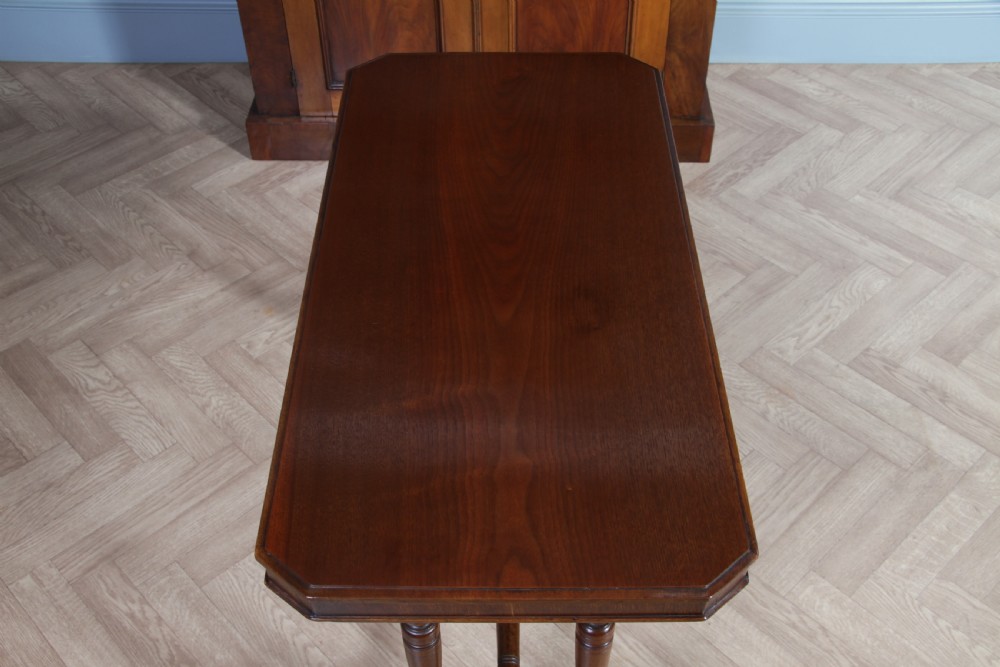 A late Victorian turned walnut occasional table featuring a rectangular top, twin turned end supports, a low stretcher, and feet set on castors. View VIII