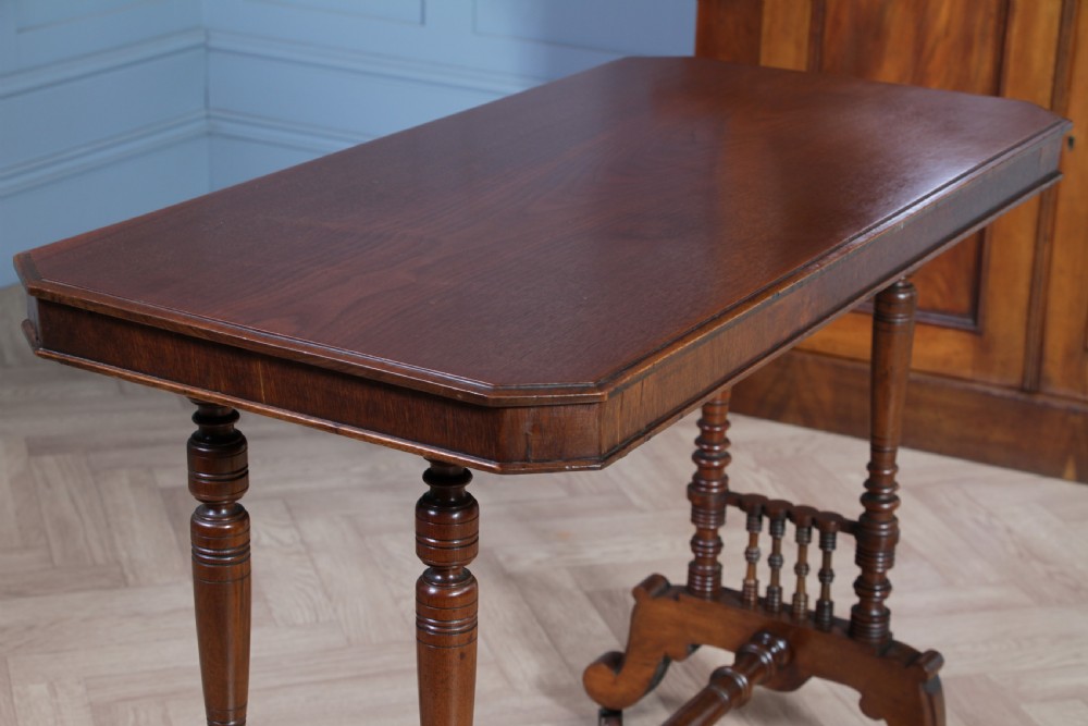 A late Victorian turned walnut occasional table featuring a rectangular top, twin turned end supports, a low stretcher, and feet set on castors. View IX