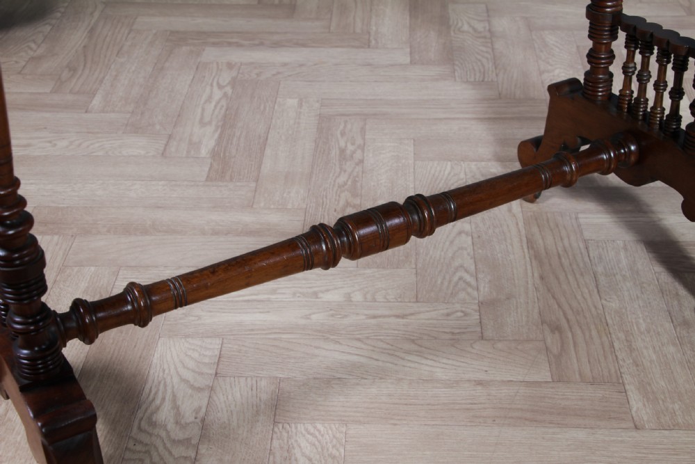 A late Victorian turned walnut occasional table featuring a rectangular top, twin turned end supports, a low stretcher, and feet set on castors. View X