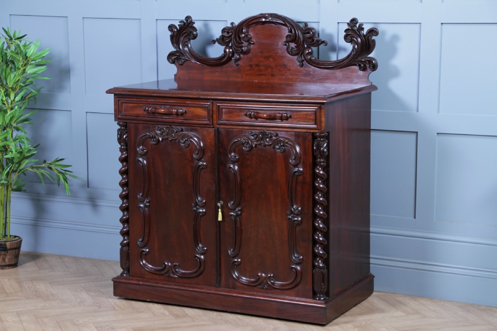 A 19th-century dark mahogany chiffonier featuring two top drawers, two carved panel cupboard doors, barley twist side columns, and a carved scroll splashback. View III