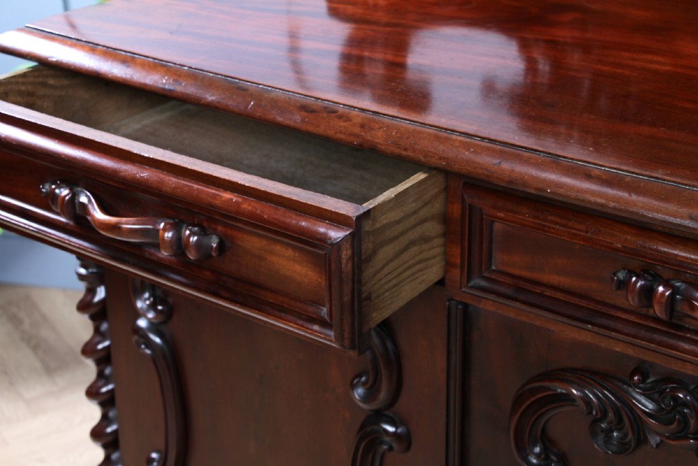 A 19th-century dark mahogany chiffonier featuring two top drawers, two carved panel cupboard doors, barley twist side columns, and a carved scroll splashback. View VII