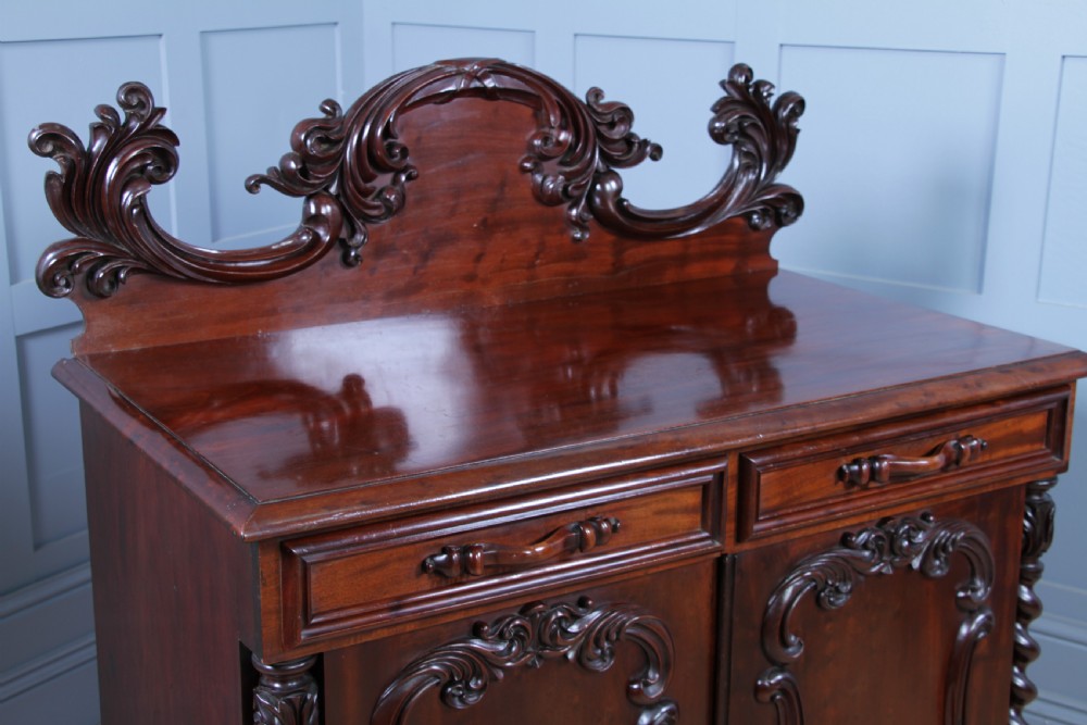 A 19th-century dark mahogany chiffonier featuring two top drawers, two carved panel cupboard doors, barley twist side columns, and a carved scroll splashback. View VIII