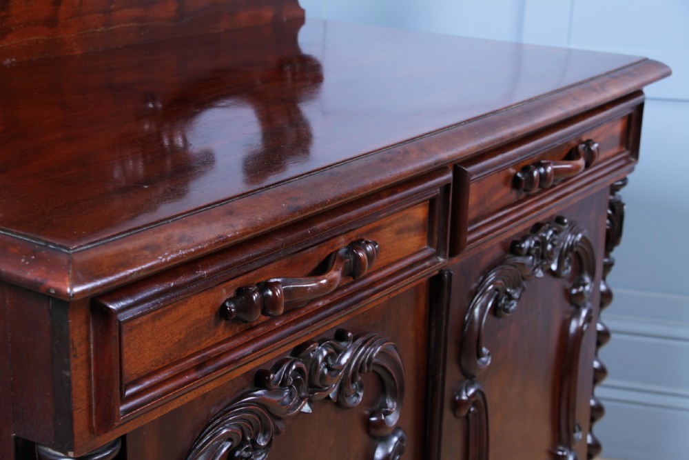 A 19th-century dark mahogany chiffonier featuring two top drawers, two carved panel cupboard doors, barley twist side columns, and a carved scroll splashback. View IX