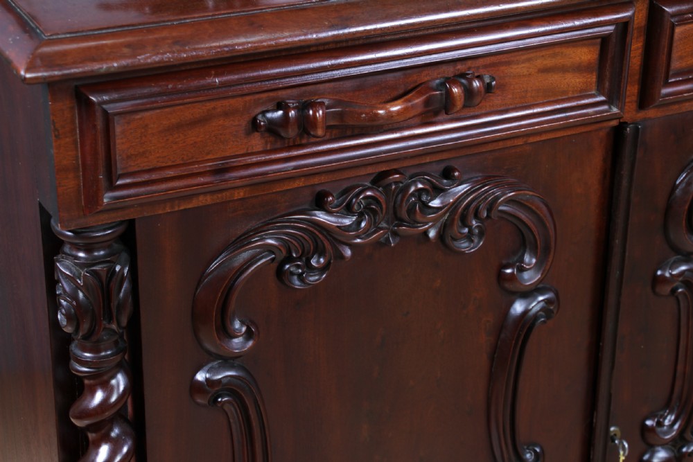 A 19th-century dark mahogany chiffonier featuring two top drawers, two carved panel cupboard doors, barley twist side columns, and a carved scroll splashback. View XI
